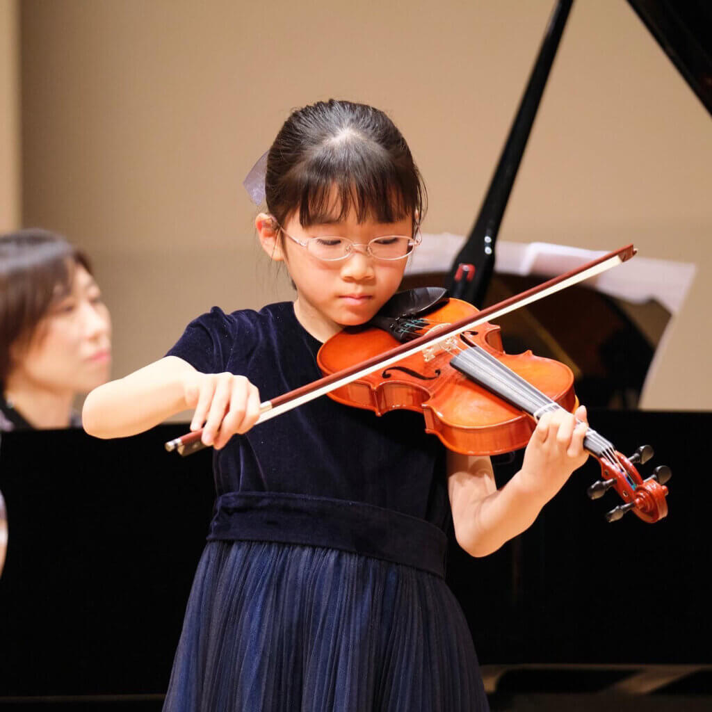 バイオリンの発表会で真剣に演奏をする女の子の写真